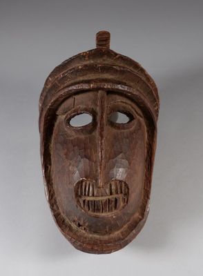 un vieux masque en bois posé sur une surface blanche, avec un fond blanc