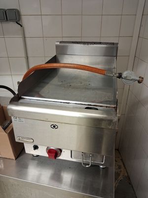 un plan de travail en acier inoxydable équipé d'une plaque de cuisson, dans une cuisine