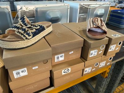 Des cartons de chaussures sont empilés les uns sur les autres dans un magasin