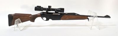 le fusil est posé sur un support transparent équipé d'une lunette de visée