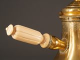 a gold tea pot with a handle and a wooden handle