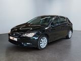 La voiture noire est garée dans une grande pièce aux murs blancs.