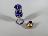 a small blue vase and a small gold object on a white surface
