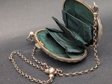 a green purse with a chain around it on a table