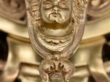 a close up of a gold vase with a face on it