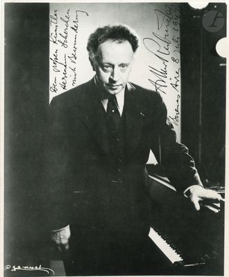 black and white photograph of a man in a suit and tie playing a piano