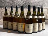 six bottles of wine are lined up in a row in front of a stone wall