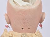 a small doll with a pink head and a pink dress
