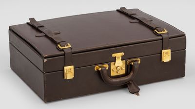 une valise marron posée sur une surface blanche