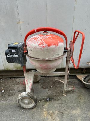 a cement mixer sitting on the ground next to a wall