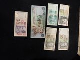 five different bank notes laid out on a black surface