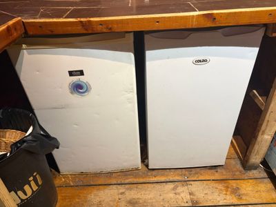 two refrigerators sitting next to each other in a kitchen