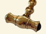 a close up picture of a gold pipe with a black bead on it