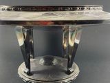 a close up of a silver plate on a stand on a table