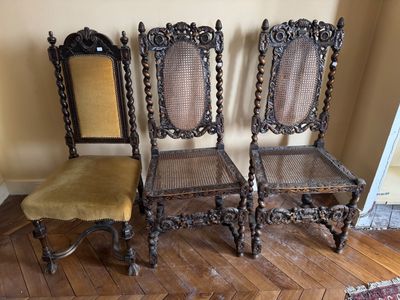 Trois chaises anciennes sont alignées contre un mur dans un salon