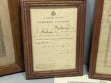 two framed photographs of a document and a certificate on a table