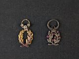 two small gold and silver charms on a black surface