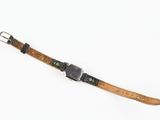 an old watch strap with a metal buckle on a white surface