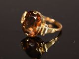 un gros plan d'une bague avec une pierre marron sur un fond noir