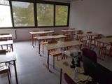 many desks and chairs in this classroom with a computer on the desk
