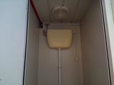 a toilet in a small room with a fan above it