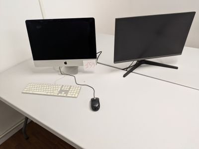 two computer monitors and a keyboard on a white desk