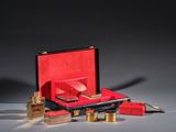 a red suitcase with a gold handle and a red box with gold accessories