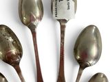 six silver spoons are arranged in a circle on a white surface