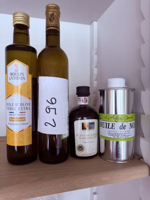 des bouteilles d'huile d'olive et d'autres ingrédients sur une étagère dans une cuisine