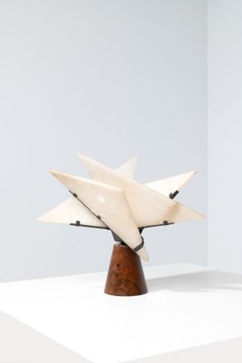 sculpture représentant une étoile blanche posée sur un socle en bois, sur une surface blanche
