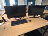 a desk with two computer monitors and a keyboard on it