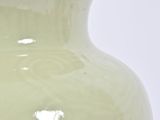 a green vase sitting on a table with a white background