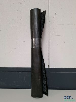 un gros plan sur un rouleau de tissu noir posé contre un mur blanc