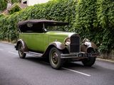 une voiture verte qui roule dans la rue devant un immeuble