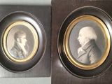 two framed portraits of two men in formal clothing, one of which is wearing a suit and the other of
