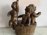 a statue of two children sitting in a wooden bucket