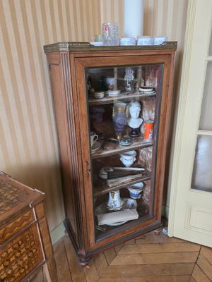 une armoire avec une porte vitrée, placée dans un coin de la pièce