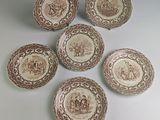 six assiettes marron et blanches sur lesquelles figurent les portraits d'un homme et d'une femme