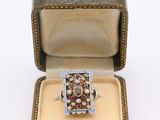 une image représentant une bague dans un écrin posé sur une surface blanche