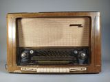 an old fashioned radio sitting on a table in front of a gray background