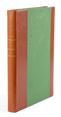 un vieux livre posé sur une table blanche, à côté d'un livre vert et marron