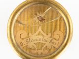 gros plan d'une montre de poche en or sur une surface blanche