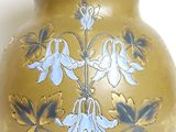 yellow vase with blue flowers on it on a white surface