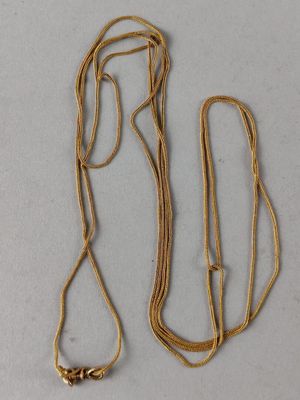 two gold necklaces with a gold chain on a white surface