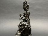 an antique bronze statue of a person sitting on top of a cow