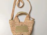 sac à main beige au crochet, muni d'une poignée et d'une étiquette en métal