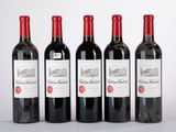 quatre bouteilles de vin rouge sont alignées sur une table