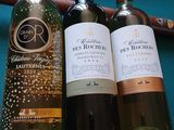 trois bouteilles de vin posées sur une table à côté d'une batte de baseball