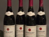 four bottles of red wine are lined up on a table
