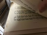 a person holding a sheet of music on top of a stack of books